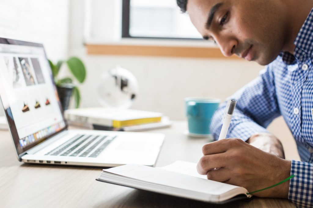 homme qui prend des notes devant un ordinateur